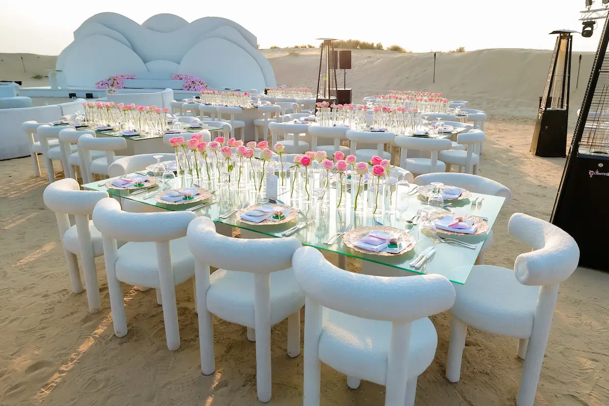 Elegant glass dining table with pink roses in bud vases set in Dubai desert