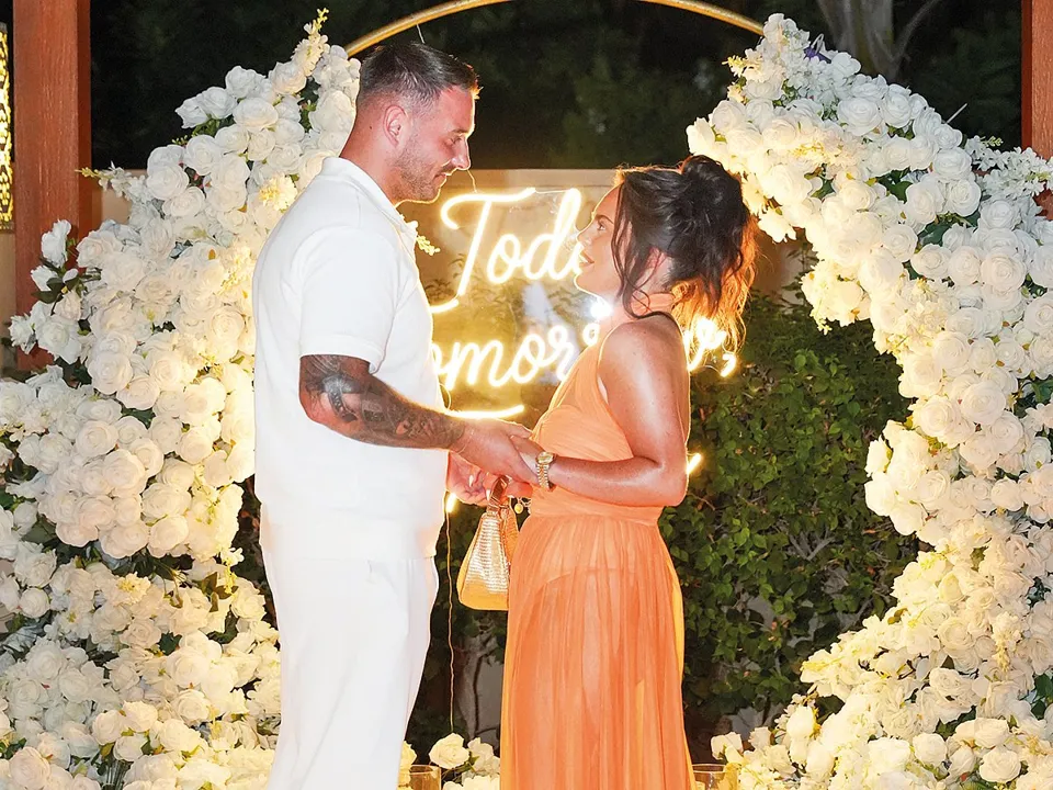 Couple at a white rose floral arch at a Dubai wedding, featured in Gulf News